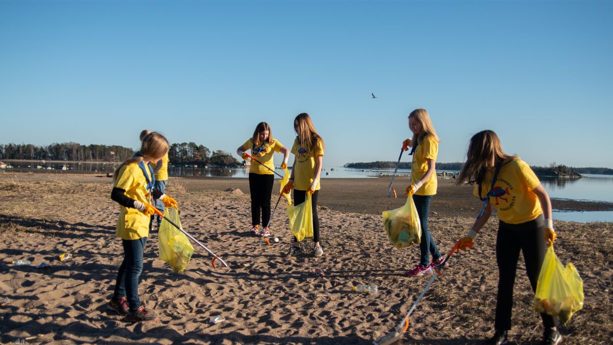 Nuoria keräämässä roskia rannalta