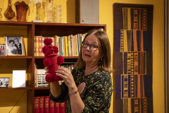 En frivillig museimormor står med en uppstoppad leksak i handen.